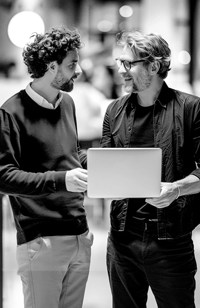Photo noir et blanc de deux collègues en discussion autour d'un ordinateur portable
