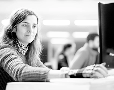 Photo en noir et blanc d'une jeune employée amputée d'une main devant un ordinateur